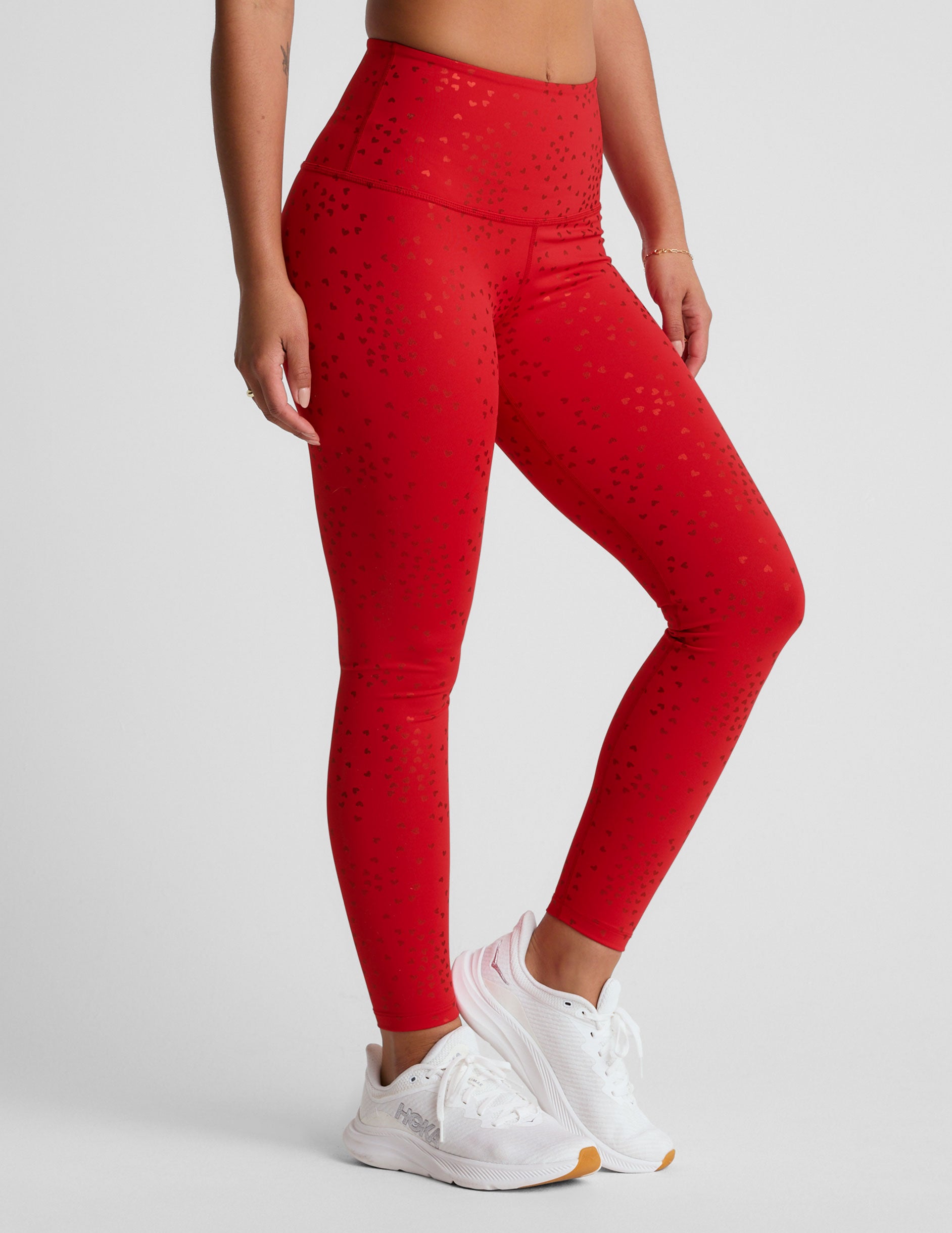 red high-waisted midi length leggings with a shimmering heart pattern. 